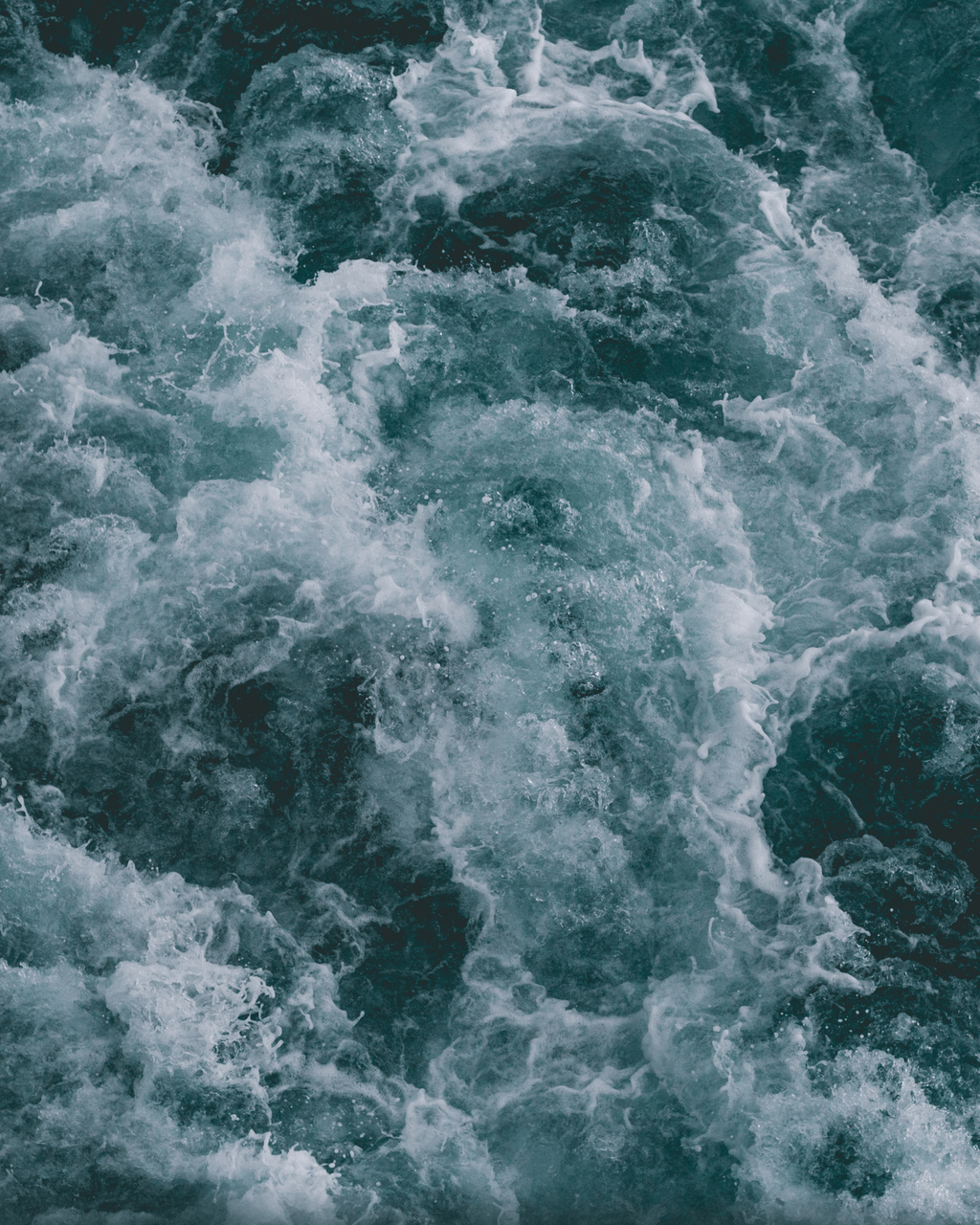 Turbulent water with frothy white waves and swirling currents, creating a textured and dynamic surface.